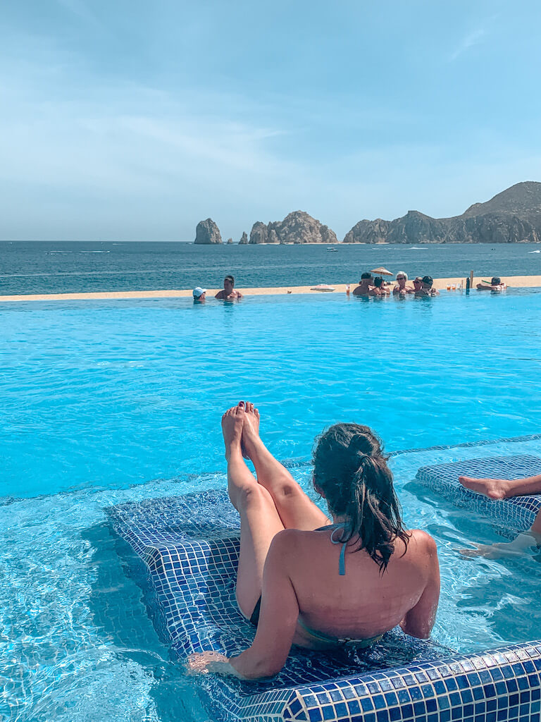 a winab sits on a tile lounger in an infinity pool at an all-inclusive resort in Cabo San Lucas, Mexico