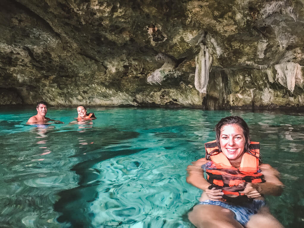 three travelers float in the dos ojos cenote in playa del carmen mexico, wearing orange life jackets