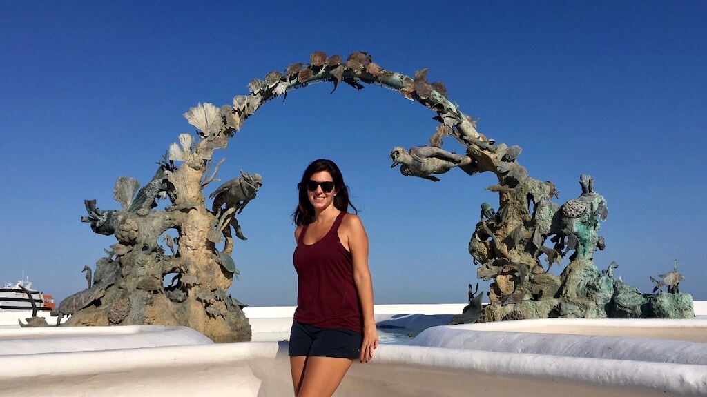 Janine posing under a concrete sculpture on Cozumel's malecon