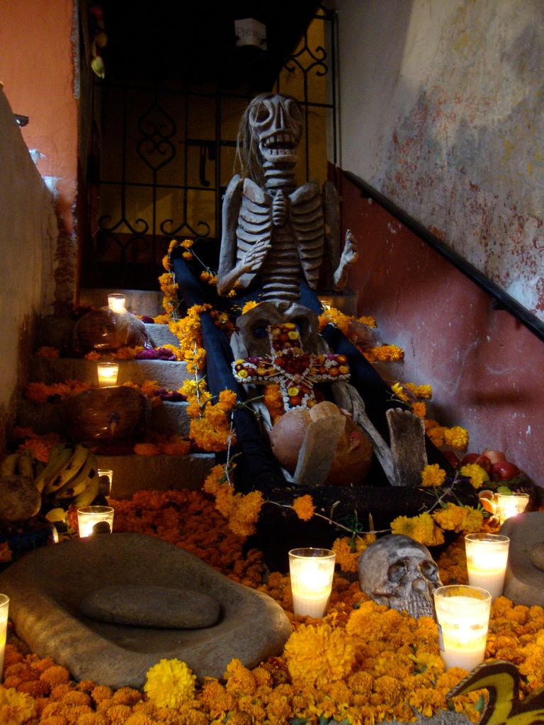 skeleton sculptures adorned with marigolds and surrounded by candles for Dia de Muertos