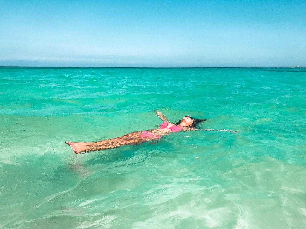 woman in a pink bikini floats on her back in the turquoise waters of the Riviera Maya