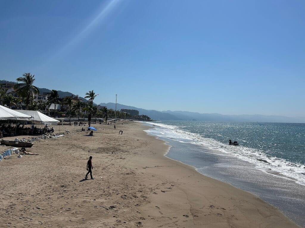 Looking south along a wide sandy beach called Playa Camarones in Puerto Vallarta, Mexico