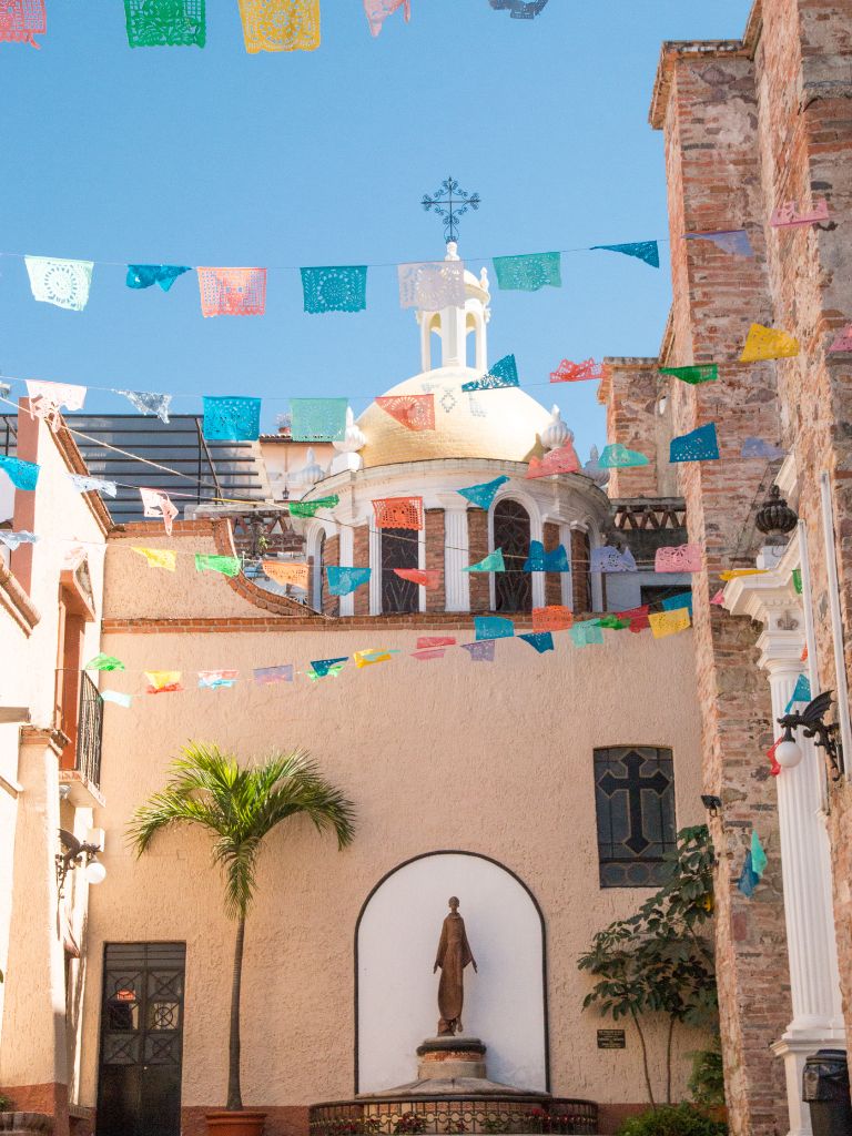 courtyard of the Cathedral Guadalupe in Puerto Vallarta with colorful papel picado strung overhead
