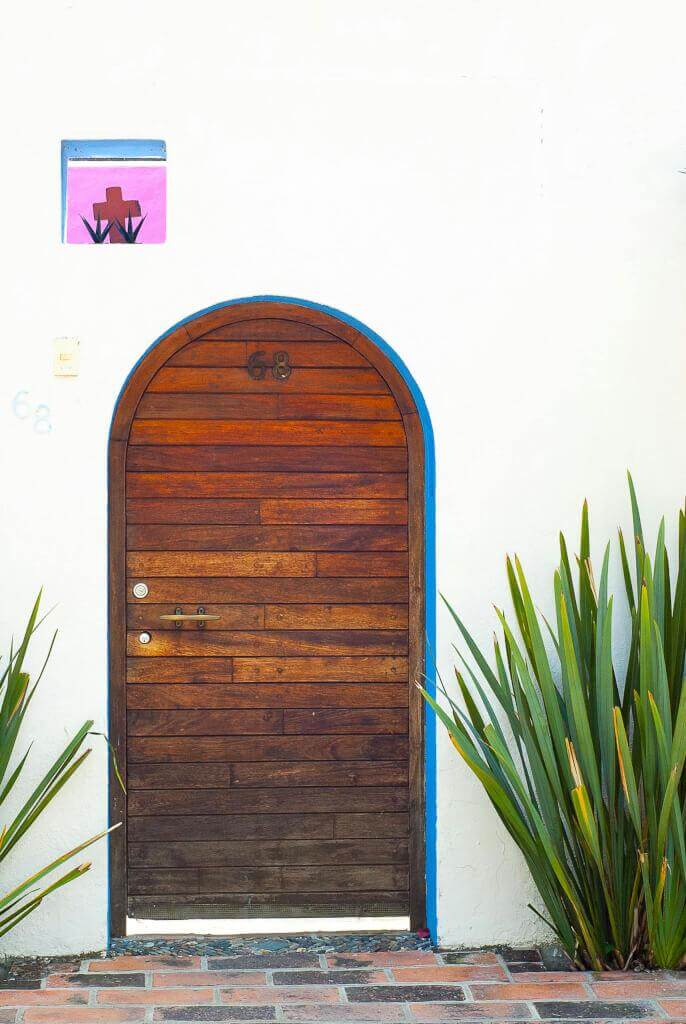 A traditional wooden arch doorway in ajijic, mexico, framed by white walls and plants.