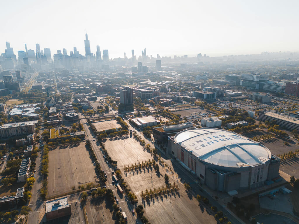 Must-Know Safety Tips When Traveling To Chicago During Winter This is an aerial view of the united center, with chicago's skyline in the background on a sunny day. It's important to follow safety tips when traveling to chicago during winter